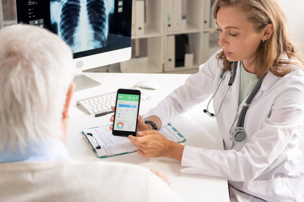 Young confident dietitian or nutritionist consulting senior patient by workplace
